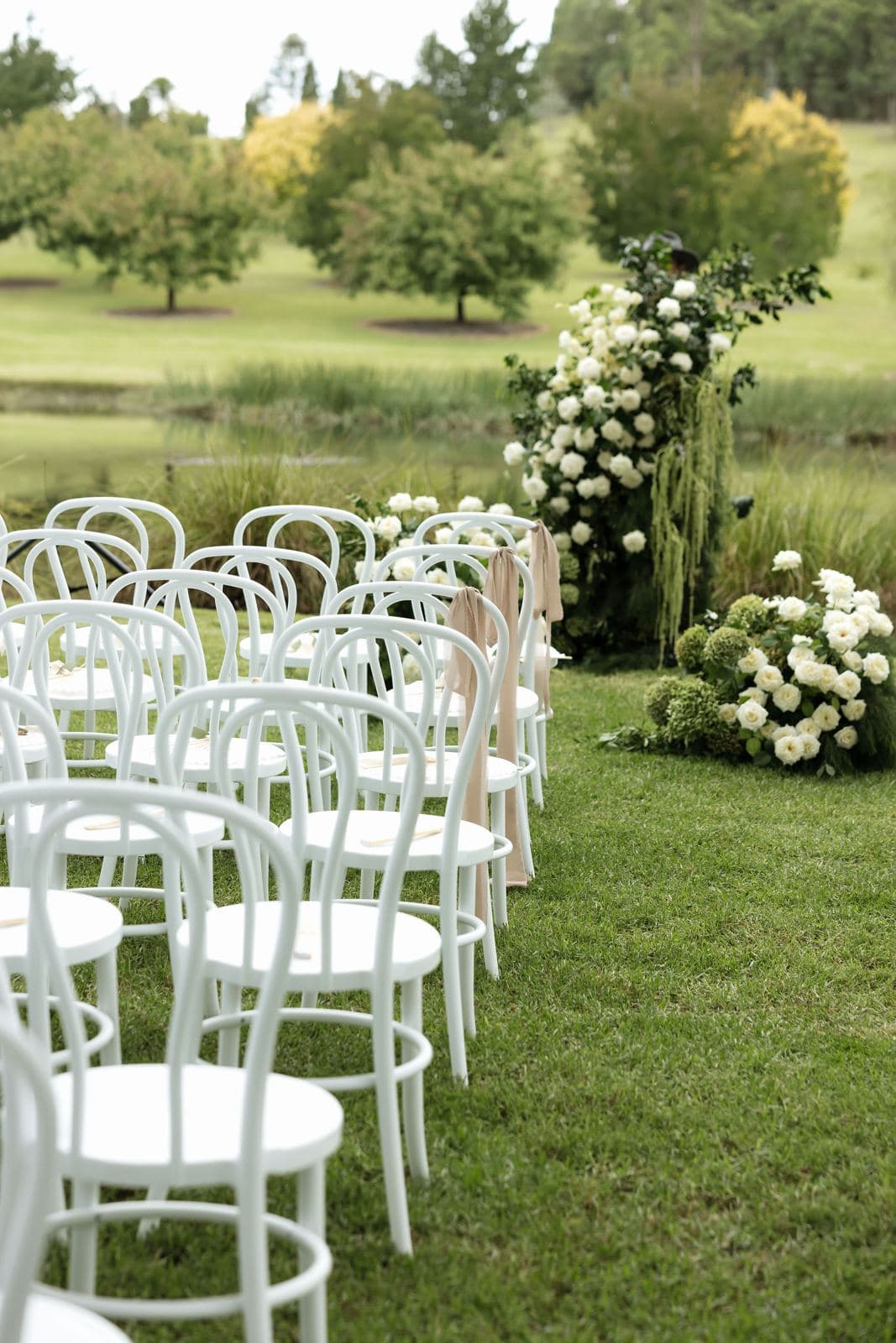 White bentwood chairs and white florals set for a garden ceremony